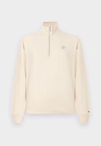 Φωτεινό μπεζ φούτερ με φερμουάρ μέχρι το στήθος και απαλό υλικό. Διαθέτει μικρό μπλε λογότυπο στο στήθος και ριμπ μανσέτες στα μανίκια.