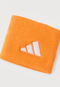 Oranžová pletená čelenka s bielym vyšitým logom s tromi pásikmi. Textúra je jemná a priliehavá.