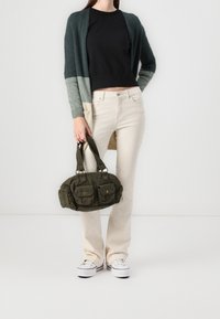 Vihreä-harmaa liukuvärinen neuletakki, musta toppi, beiget housut, valkoiset tennarit ja tummanvihreä samettikangaskäsilaukku etutaskuilla ja vetoketjuilla.