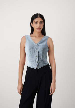 Gilet di denim azzurro chiaro con scollatura a V, bottoni frontali e due tasche laterali, abbinato a pantaloni neri a vita alta. Texture liscia.