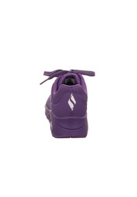 Bottines de sport violettes avec un talon arrondi, un col rembourré, un système de laçage et des détails perforés. Présente un logo sur le talon.