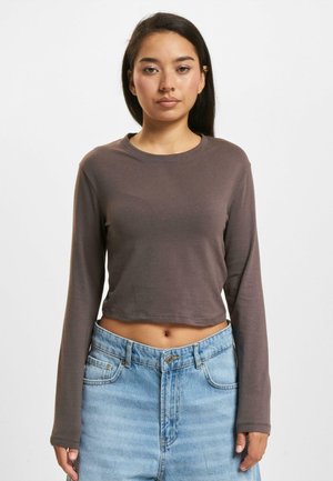 Brun lange ermer cropped topp med rund hals. Mykt stoff, avslappet passform, kombinert med lys blå høyhalsa jeans. Ingen merkbare mønstre.