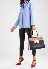 Blue and white striped button-up shirt, black leggings, red high-heeled shoes, and a multi-colored handbag with gold hardware.