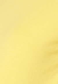 Close-up de tecido amarelo, textura suave com um ligeiro brilho, apresentando um padrão em ribetes e uma distribuição de cor uniforme.