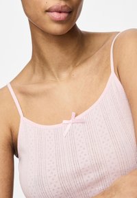 Světle růžová tílko s tenkými ramínky, s vodorovnými pruhy, výšivkou a malou mašlí v přední části.