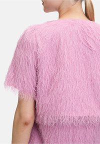 Fuzzy rosa Cropped-Top mit kurzen Ärmeln, das ein strukturiertes, schichtartiges Design aufweist. Der Stoff wirkt weich und kuschelig.
