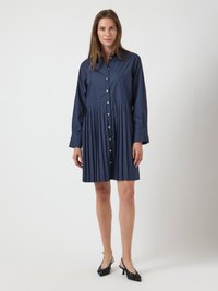 Navy blue shirt dress with a button-down front, long sleeves, and pleated skirt. Fabric appears smooth; styled with black slingback heels.