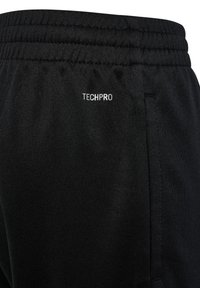 Sorte atletikbukser med elastisk taljebånd, der har en sidelomme og en lille "TECHPRO"-logo i hvid på taljebåndet.