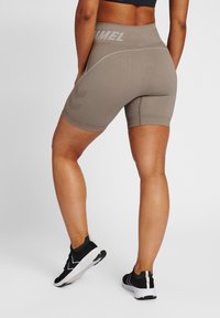 Högmidjade, ribbade beige shorts med vita detaljer, utrustade med en logotyp vid midjan och en tight passform för aktiv användning.