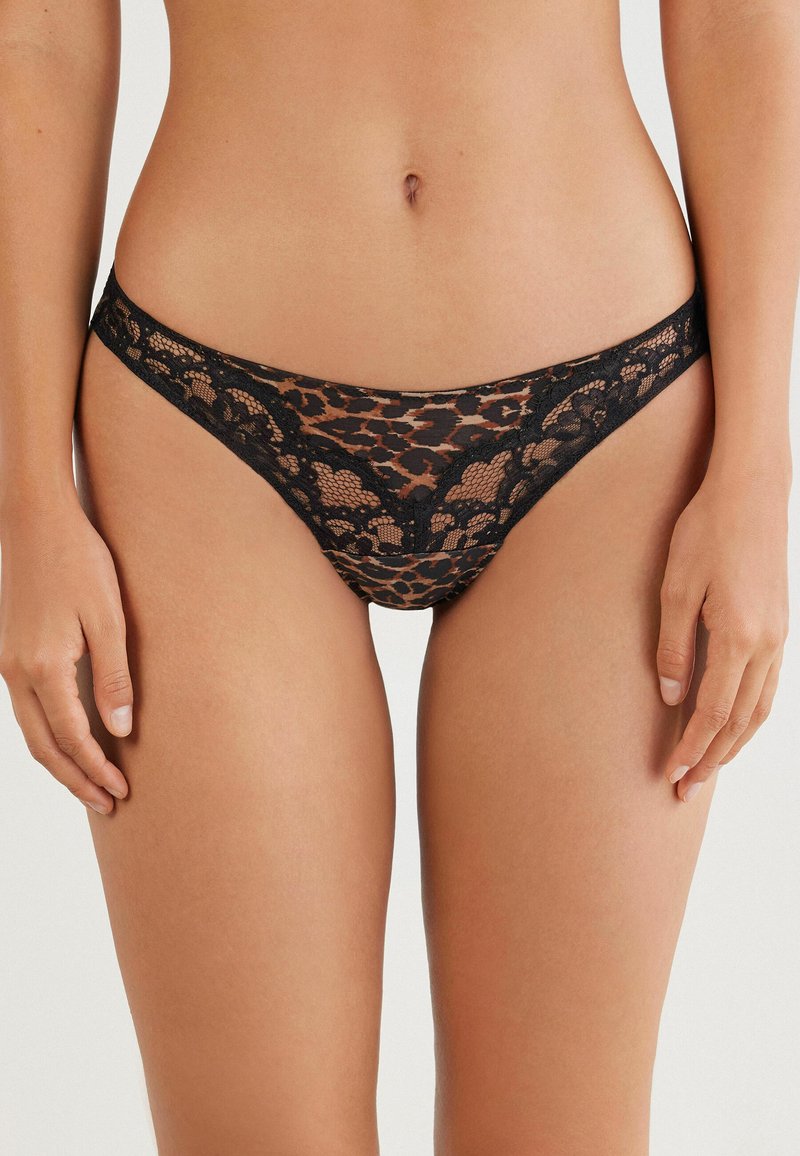 Sort blonde med leopardmønster, med en tynd talje og bølgede kanter. Gennemsigtig tekstur gennem hele designet.