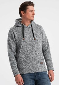Sudadera gris de punto con tejido texturizado, cordones ajustables y acentos marrones. Mangas largas y un bolsillo canguro en la parte frontal.