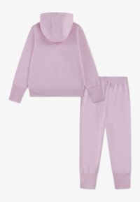 Lila pulover s kapuco iz mehkega materiala, z našito kapuco in rebrastimi zapestji, kombiniran z ujemajočimi se ohlapno zoženimi trenirkami z elastičnim pasom.