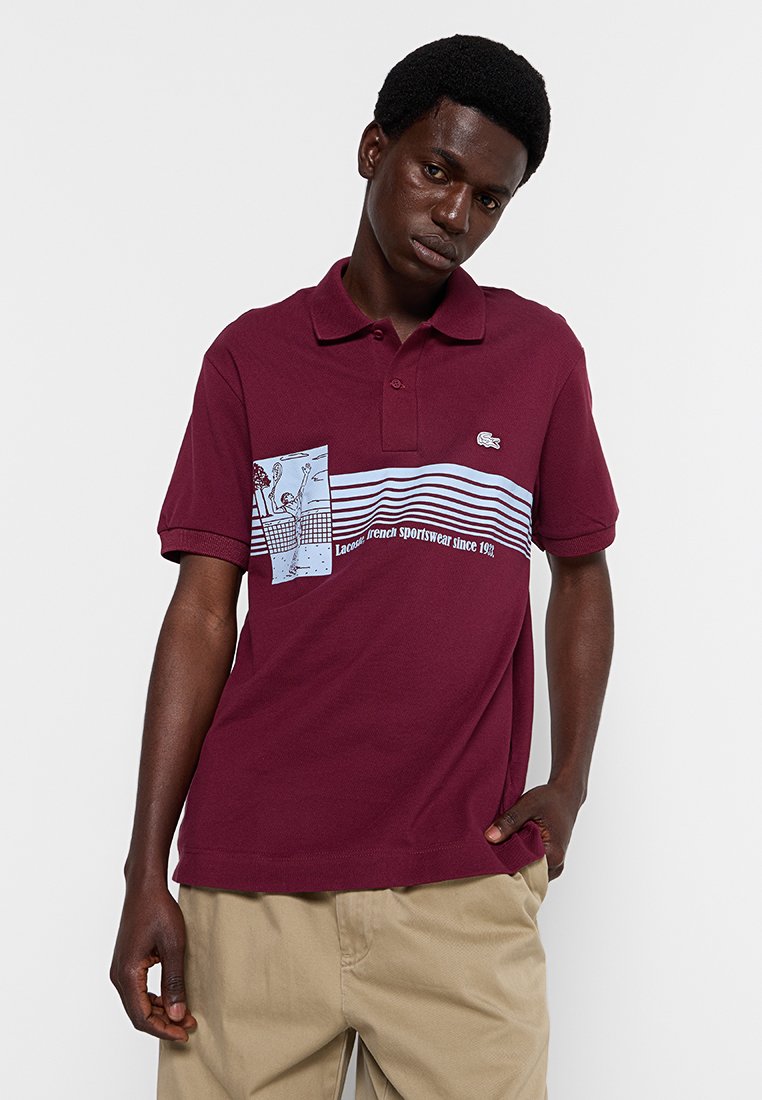 Bordowa koszulka polo wykonana z bawełny, z kołnierzykiem. Posiada graficzny nadruk na klatce piersiowej, poziome paski oraz logo z przodu.
