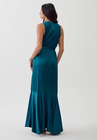 Teal sleeveless dress with a fitted bodice and flowing skirt. Smooth satin fabric, flared bottom, and a belted waist for shape.