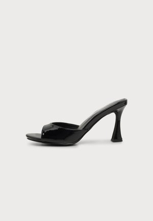 Mule negro de charol con puntera abierta, tacón alto curvado y diseño fácil de poner, mostrado de lado sobre fondo blanco.
