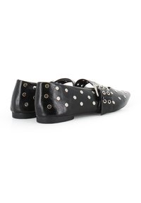 Bailarinas de cuero negro con punta afilada, que presentan tachuelas plateadas y detalles de ojales. Tacón bajo, diseño recortado y acentos decorativos en las correas.