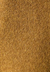 Nahaufnahme von grobem, strukturiertem senfgelbem Strickstoff mit sichtbaren Garnsträngen und vertikalen Stichmustern.