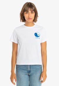 White cotton t-shirt with a round neckline and short sleeves. Features a blue yin-yang graphic with "RVCA" text beside it.