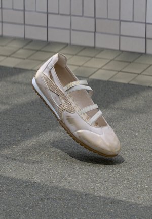 Baskets beige clair avec accents à texture reptile, bandes blanches et semelle en caoutchouc flexible. Présente une finition lisse et des découpes latérales.