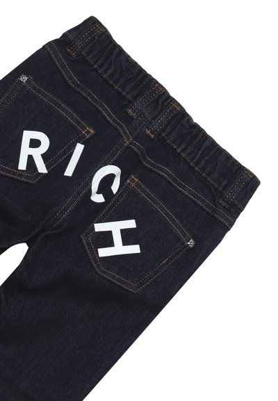 Jeans in denim scuro con una fascia elastica in vita, caratterizzati da lettere bianche in blocco che formano la parola "RICH" sulle tasche posteriori e dettagli di cucitura arancione.