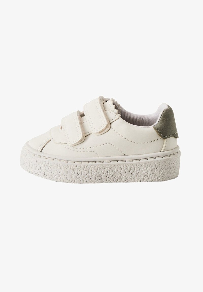 Baskets blanches en cuir avec des bandes Velcro, semelle blanche texturée et un accent vert sur le talon. Bout arrondi et détails cousus.