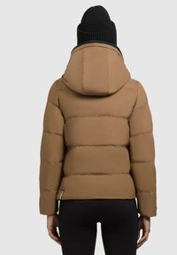 Geacă puffer maro cu glugă, având secțiuni horizontale matlasate și o textură netedă. Căciulă neagră din tricot purtată pe cap.