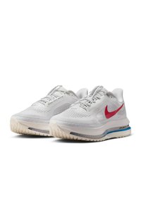 Baskets blanches en tissu aéré, avec un swoosh rouge de Nike, un col rembourré, un amorti visible et une semelle extérieure en caoutchouc texturé.