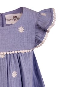 Světle fialové šaty z látky s volánovými rukávy, dekorativní bílou výšivkou a střapcovým lemem podél výstřihu a spodního okraje.