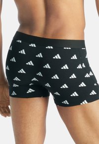 Svarta boxershorts med ett upprepande vitt triangelmönster. Mjukt tyg med en bekväm elastisk midja.