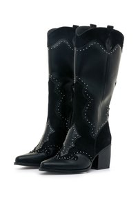 Botas de vaquero negras de cuero y ante con punta afilada, diseños en relieve y tachuelas plateadas, y con un tacón bloque de altura media.