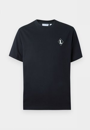 T-shirt nera a maniche corte con scollo a girocollo, con un piccolo logo bianco a forma di diamante contenente la lettera "L" sul lato sinistro del petto.