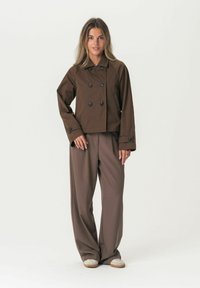 Brown cropped double-breasted jacket with black buttons, paired with loose, brown wide-leg trousers. Smooth fabric with a clean design.