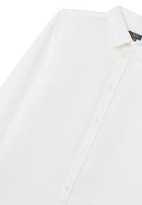 Camisa blanca de manga larga hecha de tela ligera, con cuello tipo button-down y cierre frontal de botones. Textura suave con un ligero brillo.