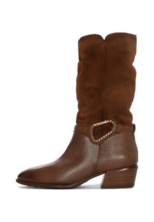 Botte en suède marron à hauteur de genou avec un orteil en cuir texturé, accentuée par une boucle ovale décorative et un talon empilé.