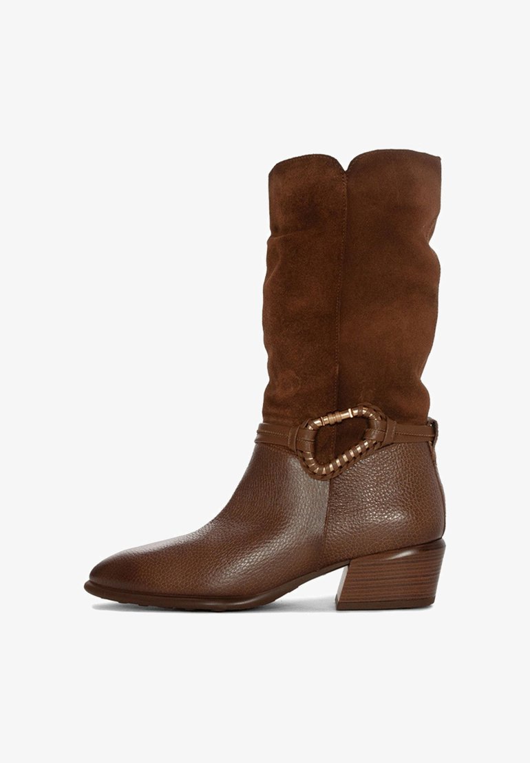 Bota alta de ante marrón con puntera de cuero texturizado, acentuada por una hebilla ovalada decorativa y un tacón apilado.