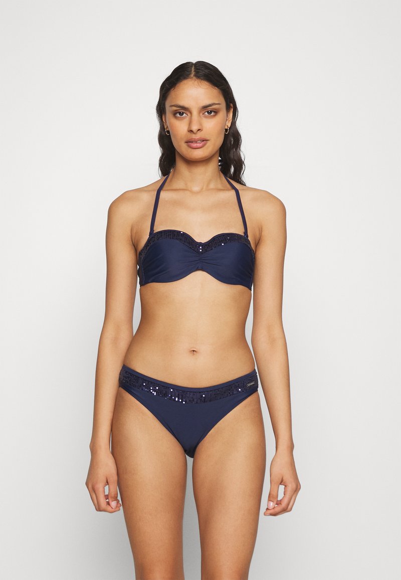 Natanje modri bikini komplet, ki vključuje nabran bandeau zgornji del s sijočimi dodatki in usklajene spodnje hlačke z okrasnim sijočim pasom.