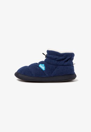 Bota de zapatilla interior azul marino suave con suela negra, forro interior de forro polar blanco, cordón ajustable y parche con logo azul en el lateral.