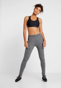 Svart sport-bh och grå, strukturerade, höga midjeleggings. Leggingsen har en figurnära design och ett elastiskt midjeband, lämpliga för atletisk användning.