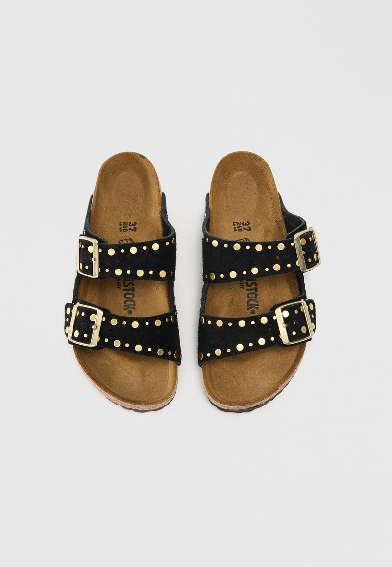 Zwarte suede sandaal met twee verstelbare gespen, voorzien van gouden studs langs de banden en een bruine kurken voetbed.