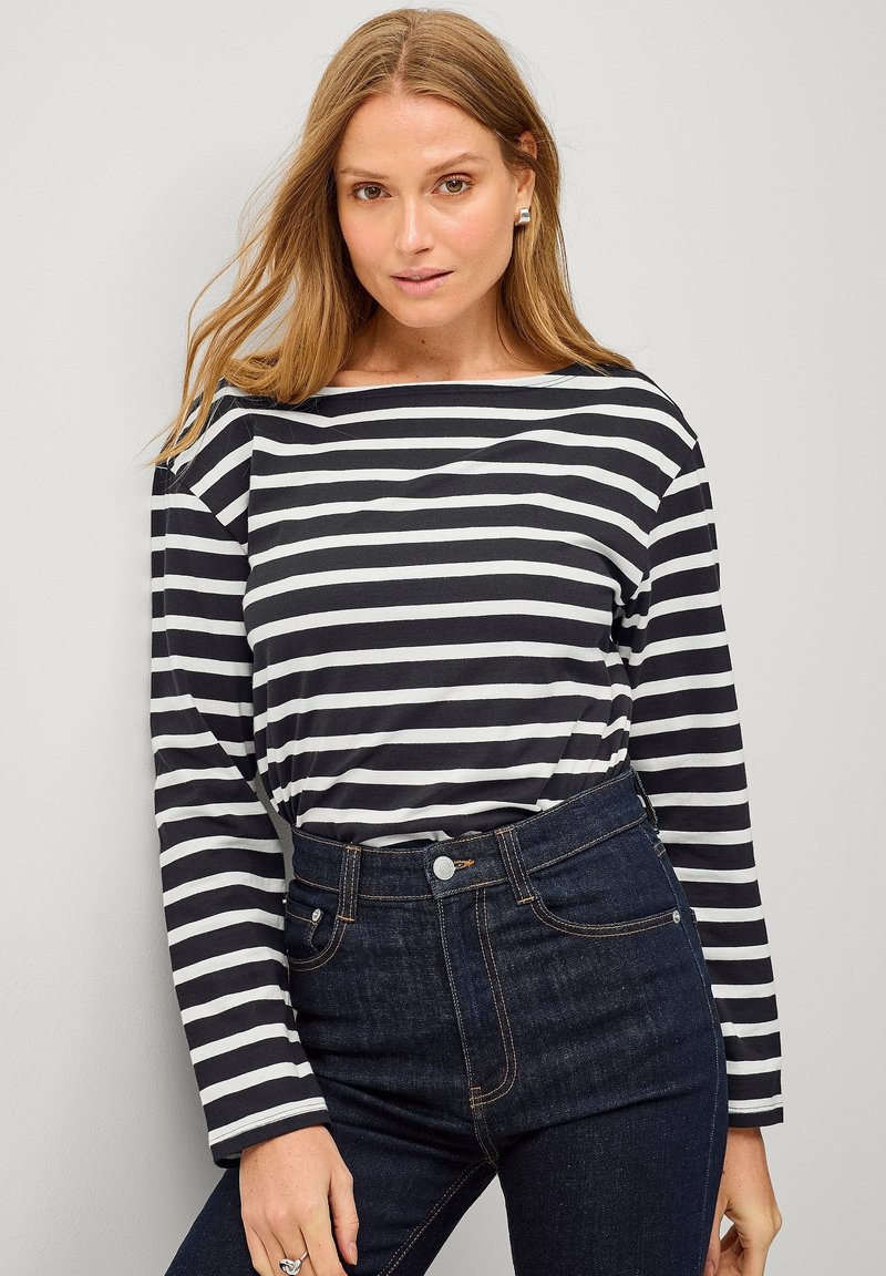 Lange mouw top met marineblauwe en witte horizontale strepen, gemaakt van een zachte stof, gecombineerd met donkere, hoge taillejeans.