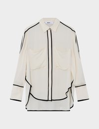 Ανοιχτόκrem πουκάμισο με μαύρες ραφές, εμπρόσθιο κούμπωμα με κουμπιά, δύο τσέπες στο στήθος, μακριά μανίκια και καμπύλη γραμμή στο τελείωμα. Λεία υφή υφάσματος.