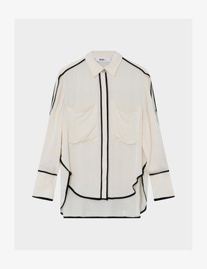 Ανοιχτόκrem πουκάμισο με μαύρες ραφές, εμπρόσθιο κούμπωμα με κουμπιά, δύο τσέπες στο στήθος, μακριά μανίκια και καμπύλη γραμμή στο τελείωμα. Λεία υφή υφάσματος.