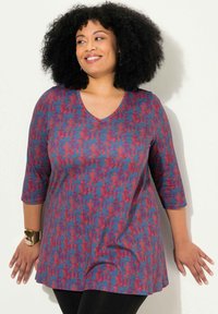 V-hals tuniek met driekwart mouwen, met een blauw en rood abstract patroon op een zachte, rekbare stof. Taillering met een uitlopende zoom.