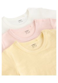 Trois t-shirts pour bébé en coton blanc, rose et jaune. Chacun présente un col rond et des boutons-pression à l'épaule pour un habillage facile.