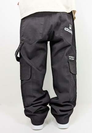 Black cargo pants with a loose fit, featuring side pockets, stitched details, and a printed message on the right pocket. Made of durable fabric.