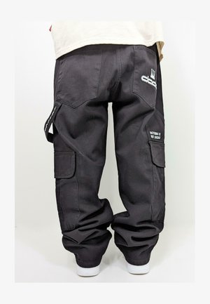 Black cargo pants with a loose fit, featuring side pockets, stitched details, and a printed message on the right pocket. Made of durable fabric.