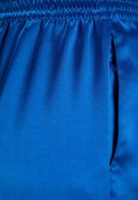 Blue satin fabric with a smooth texture, featuring an elastic waistband and a side slit for added detail and movement.