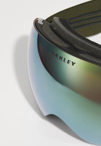Skibril met een gebogen, reflecterende lens met een groenige tint, donkere montuur en een gestructureerde band met een olijfgroene accent. Gegraveerde merknaam.