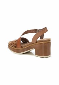 Sandalo con tacco in pelle marrone, design perforato, cinturino incrociato, soletta imbottita e tacco massiccio. Suola strutturata per una migliore aderenza.