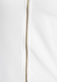 White zip-up garment featuring a gold-tone zipper, smooth texture, and subtle stitching along the sides. Minimalist design.